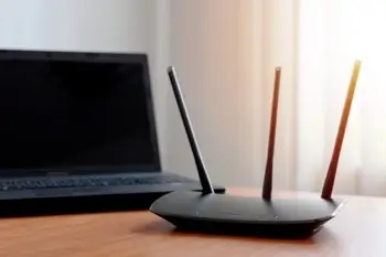 A router with an SSID on a table next to a computer